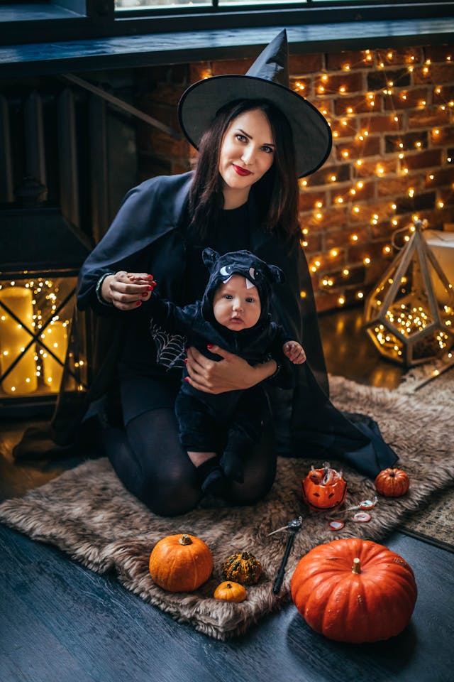 Maman déguisée en sorcière et son bébé célébrant Halloween avec des bougies